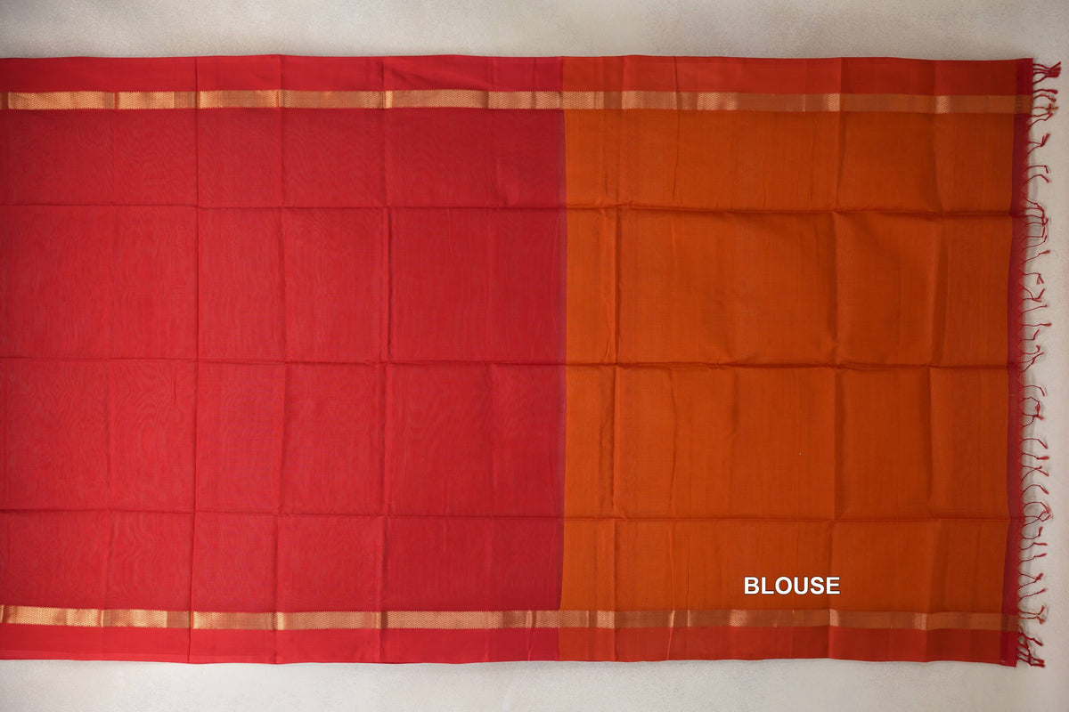 Maheshwari silk-cotton saree laid flat, with a vermilion red body beside a deep orange blouse piece, narrow gold-toned border stripes and tassels.
