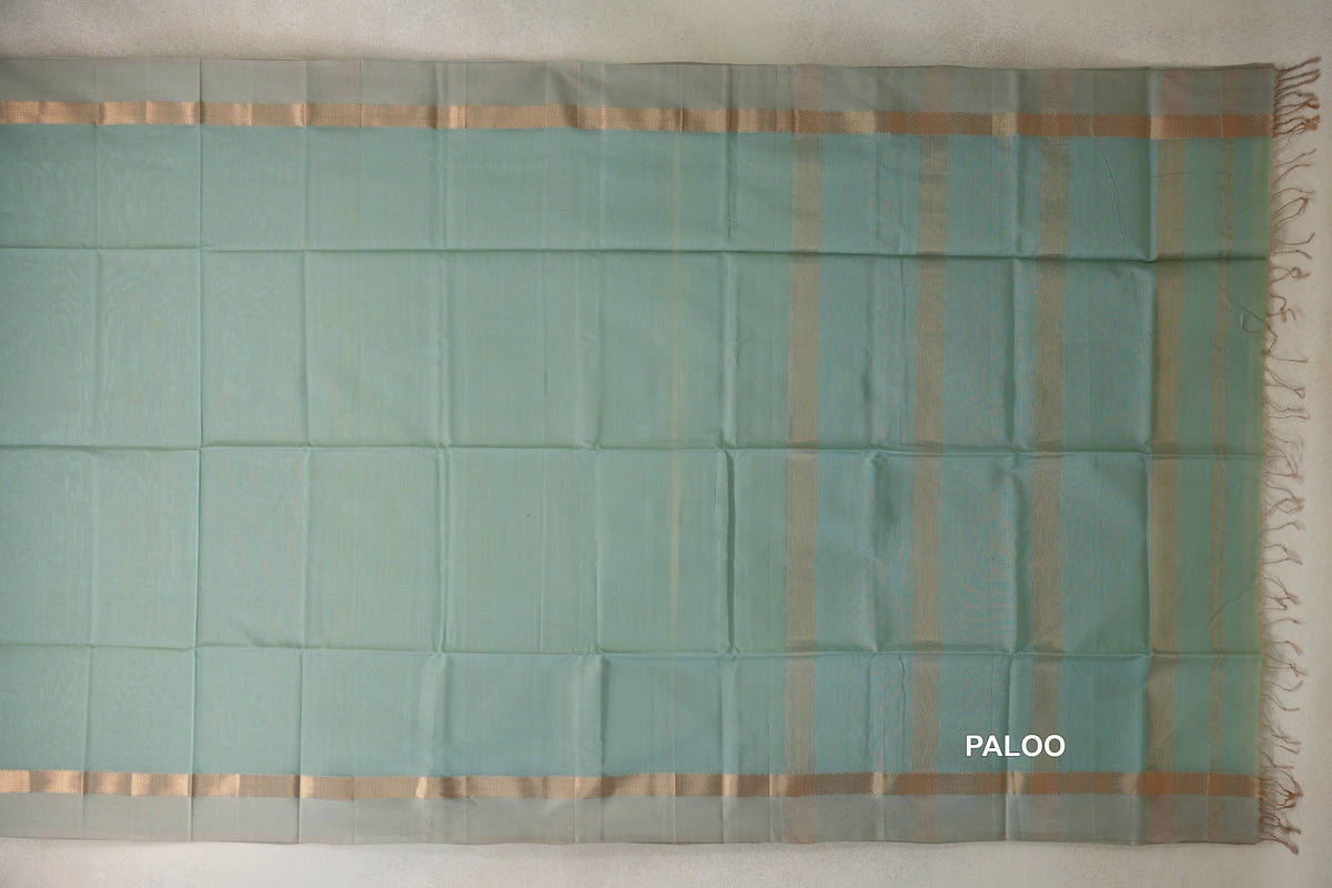 Sea green Maheshwari silk cotton saree laid flat, with light sandal beige borders and a gold zari-striped pallu with tassels.