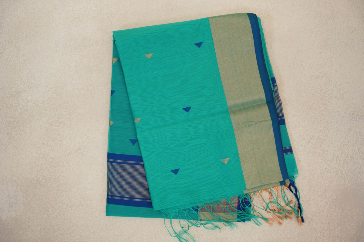 Folded sea green Maheshwari silk cotton saree with small blue and gold triangles, a pale gold border edged in blue, striped section and tassels.