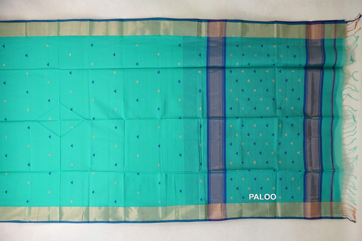 Sea green Maheshwari silk cotton saree laid flat, with scattered blue and cream triangles, blue-edged borders and a striped pallu with tassels.