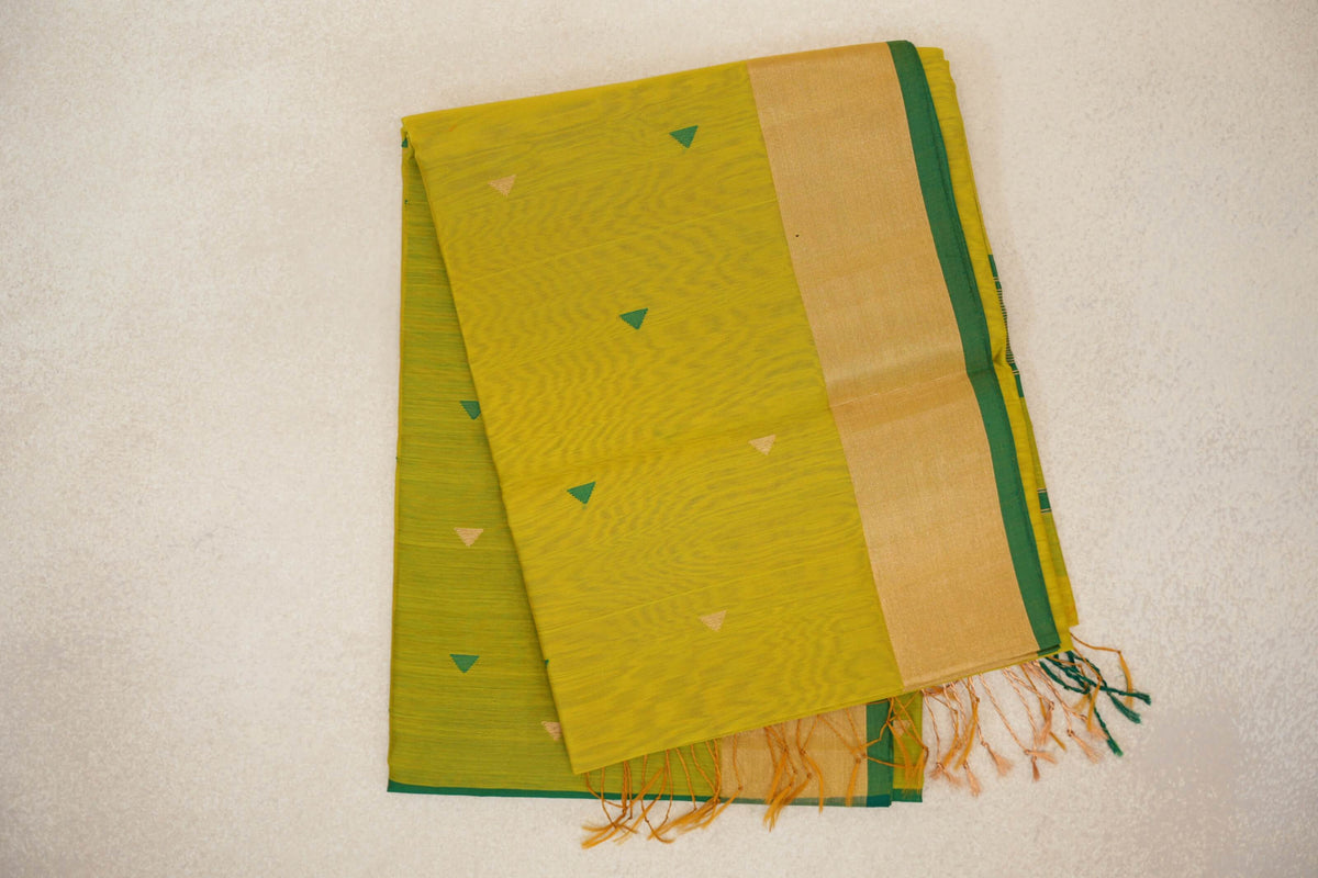 Folded bright lemon yellow Maheshwari silk cotton saree with small green and gold triangles, a broad gold band, leaf green edging and tassels.