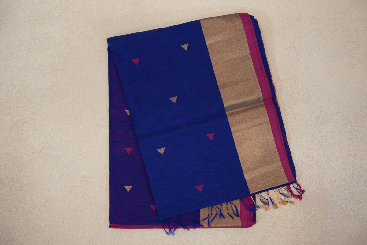 Folded bright royal blue Maheshwari silk cotton saree with small pink and gold triangles, a broad gold-coloured border edged in rani pink, and tassels.