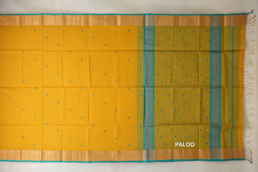 Mustard yellow Maheshwari silk-cotton saree laid flat, with tiny triangular motifs, turquoise-edged borders and a striped pallu with tassels.