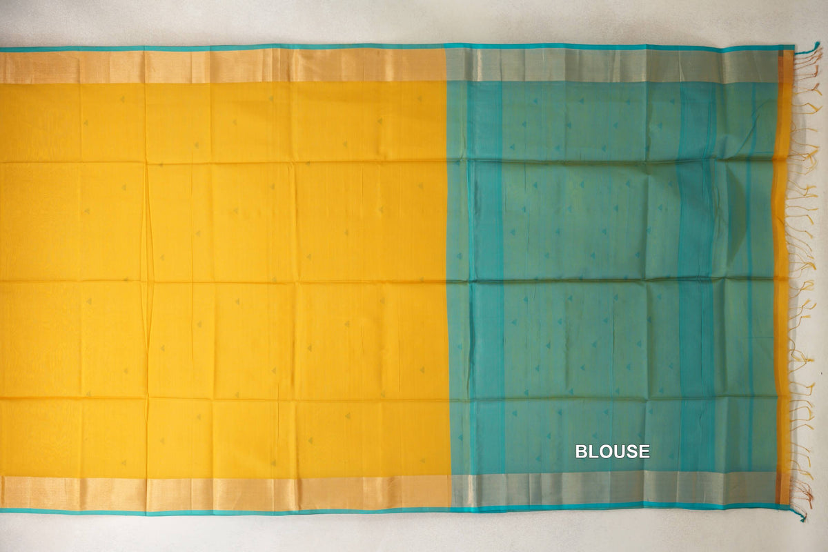 Maheshwari silk-cotton saree laid flat, showing a mustard yellow body with tiny motifs, turquoise-edged borders and a turquoise blue blouse section.