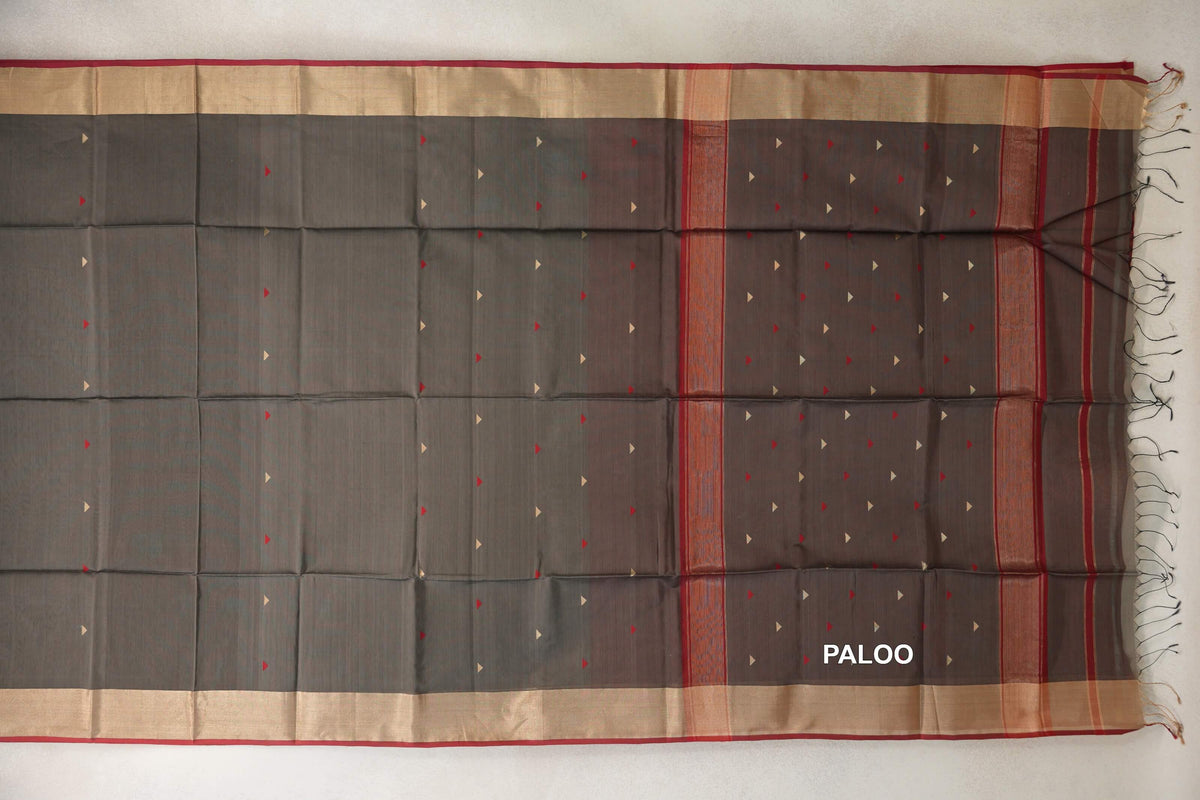 Charcoal grey Maheshwari silk-cotton saree spread flat, with small red and pale triangles, wide pale borders with deep red edging, and a fringed pallu.