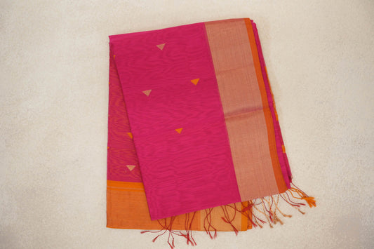 Folded rani pink Maheshwari silk cotton saree with small triangular motifs, a broad orange border and loose tassels at one end.