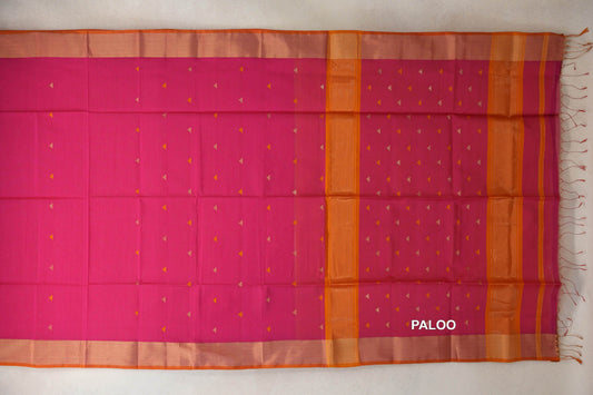Rani pink Maheshwari silk cotton saree laid flat, with small triangle motifs, orange borders and a banded pallu with tassels.