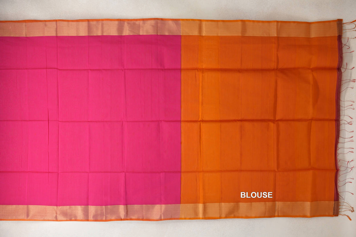 Maheshwari silk cotton saree laid flat, with a plain rani pink body, orange blouse section, pale orange borders and tassels at one end.