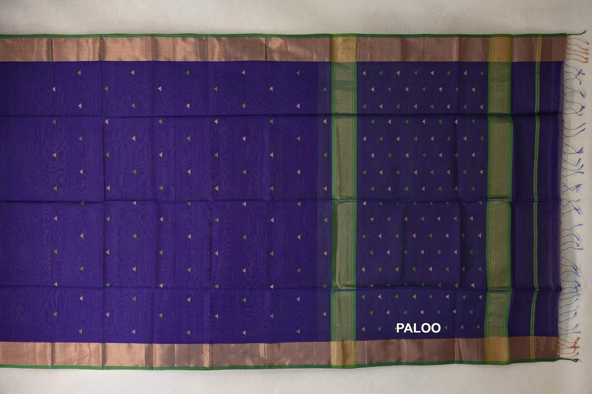 Deep violet Maheshwari silk cotton saree laid open, showing small green and gold triangles, a striped pallu, green-edged borders and tassels.