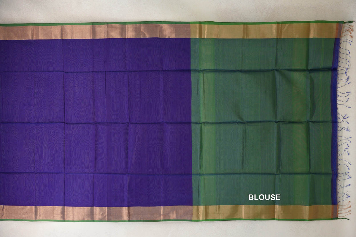 Deep violet Maheshwari silk cotton saree laid flat beside a leaf green blouse piece, with metallic-toned borders, green edging and tassels.