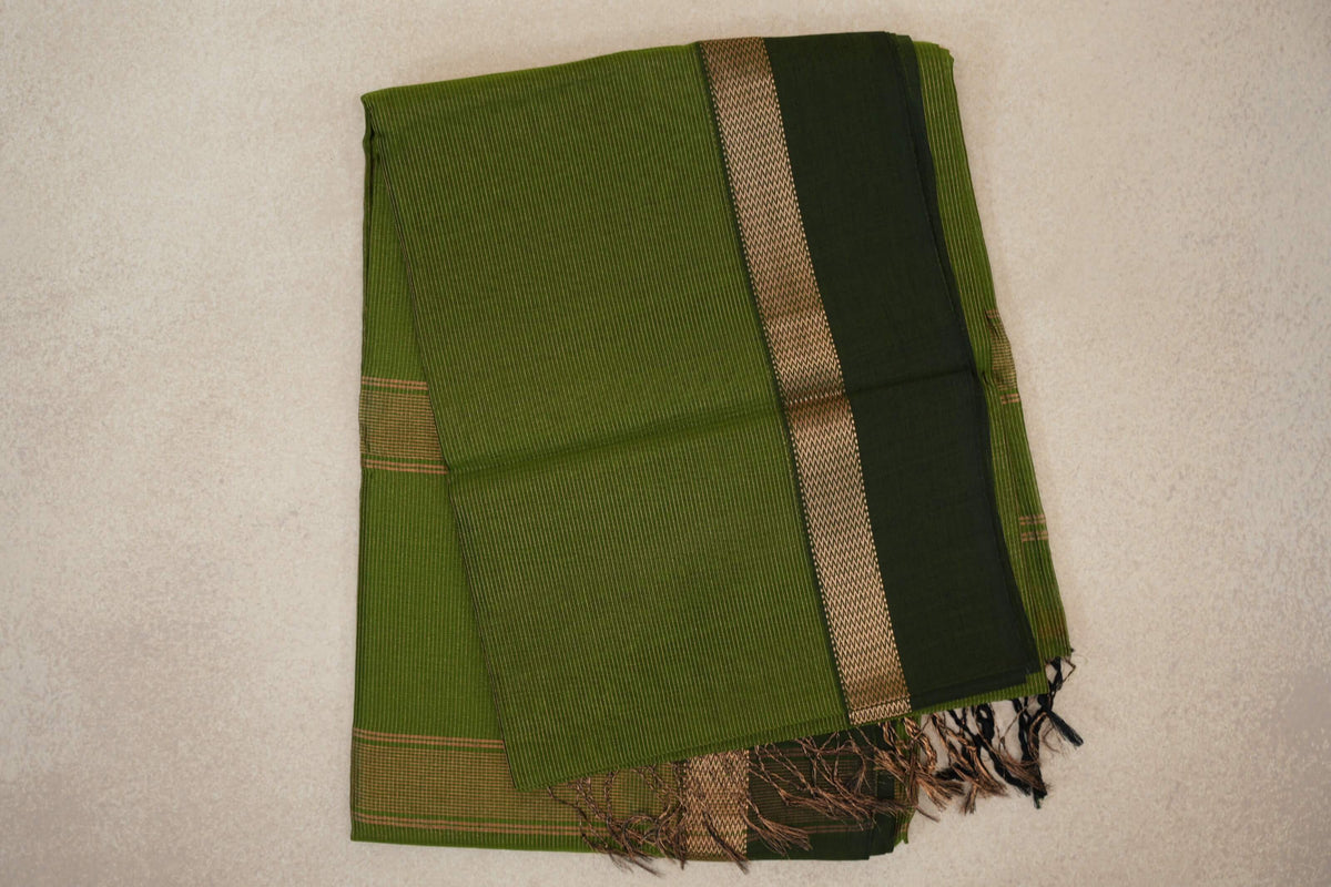 Folded olive green Maheshwari silk cotton saree with fine stripes, a deep forest green border, a patterned band and tassels.