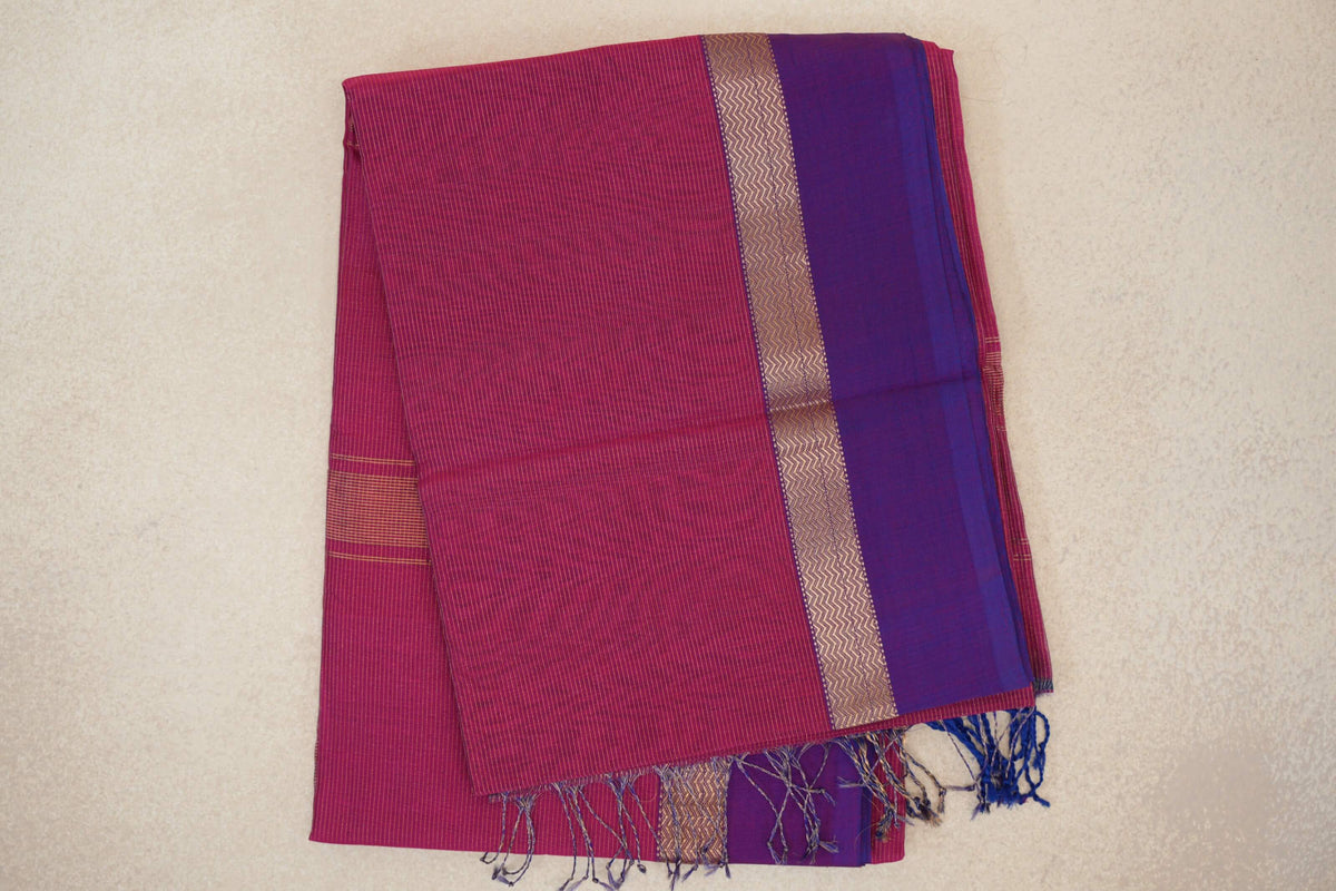 Folded Deep Rani Pink Maheshwari silk cotton saree with fine stripes, a Violet Purple border, zigzag-patterned band and tasselled edge.