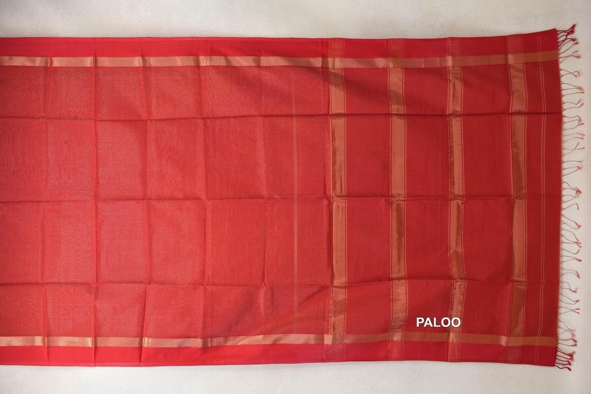 Red Maheshwari silk-cotton saree laid flat, showing a plain body, narrow gold-toned borders and a striped pallu with red tassels.