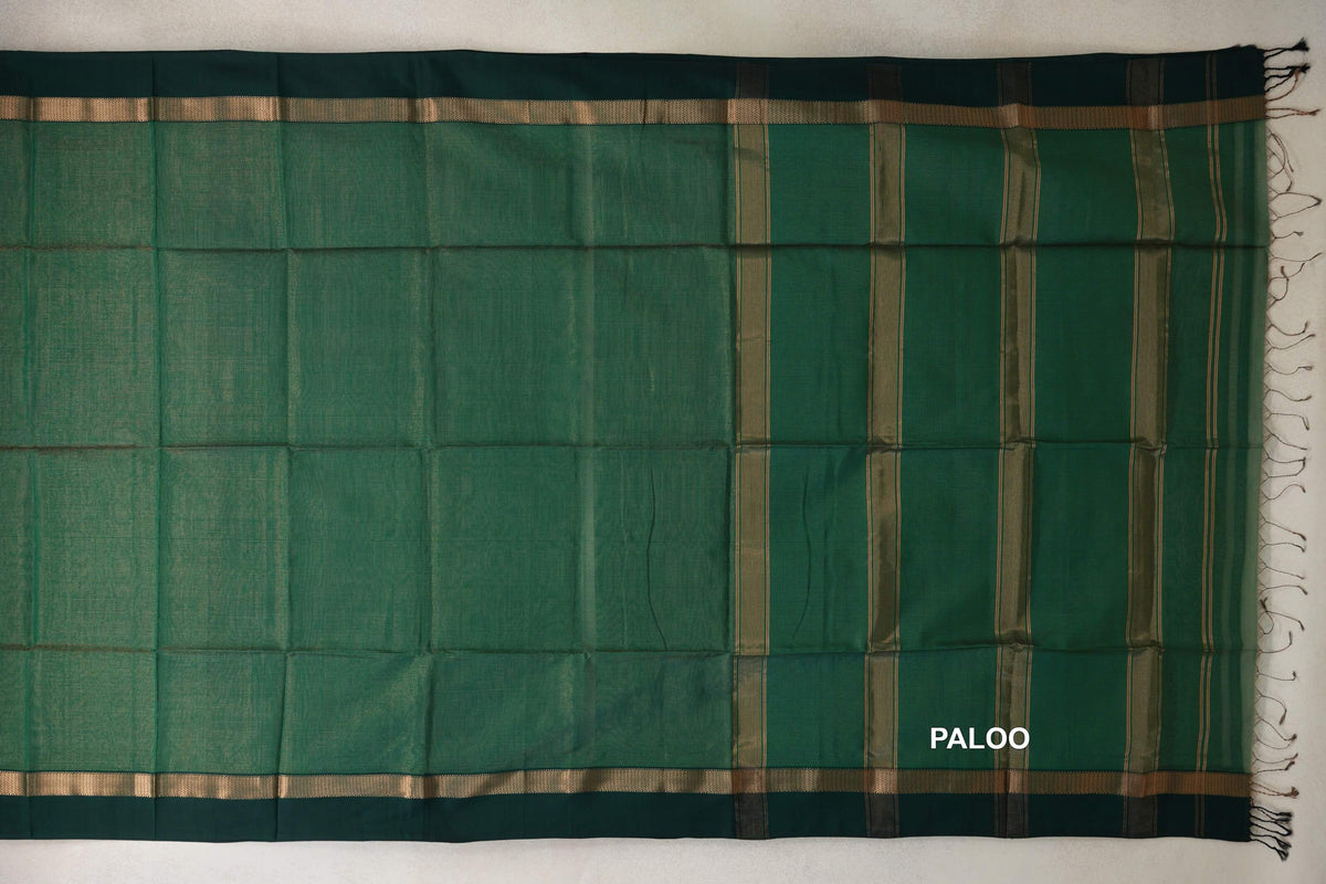 Bottle green Maheshwari silk cotton saree laid flat, showing a striped pallu with tassels and dark bottle green borders with gold bands.