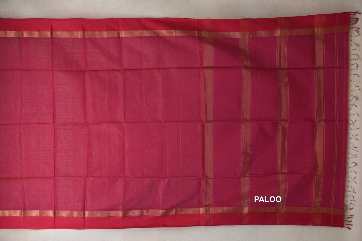 Rani Pink Maheshwari silk cotton saree laid flat, showing a plain body, gold-toned border bands and a striped pallu with tassels.