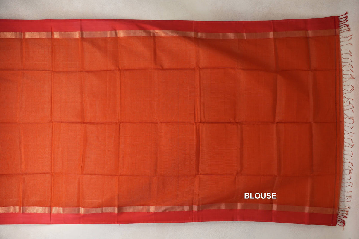 Rust orange Maheshwari silk cotton blouse piece laid flat, with red borders, narrow gold-toned stripes and fringe along one edge.