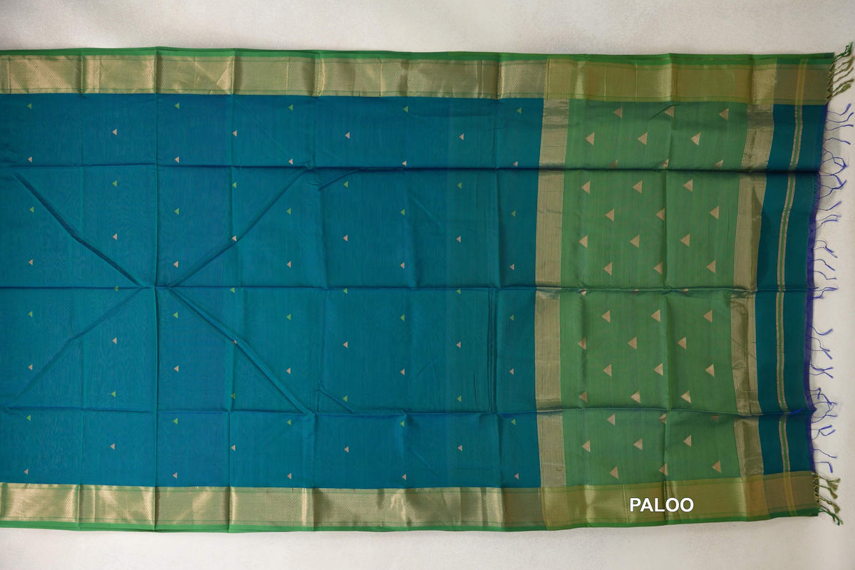 Maheshwari silk-cotton saree laid flat, with a peacock green body dotted with small triangles, leaf green borders and a fringed pallu.