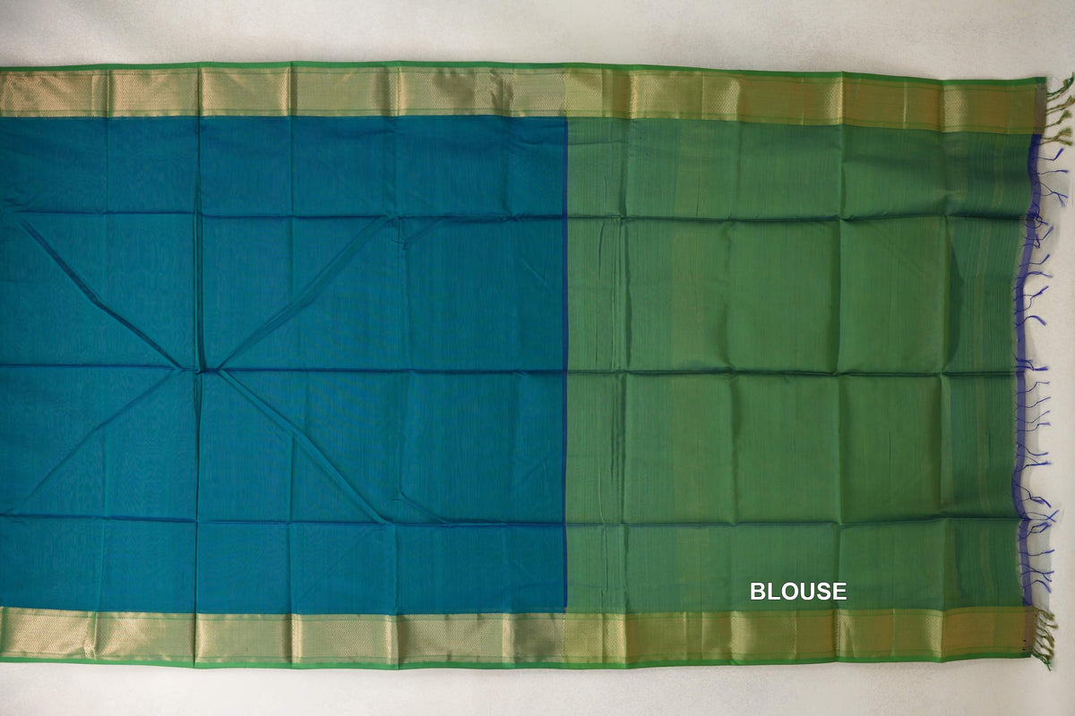 Maheshwari silk-cotton saree spread flat, showing a peacock green body, leaf green blouse section, gold-toned woven borders and tassels.