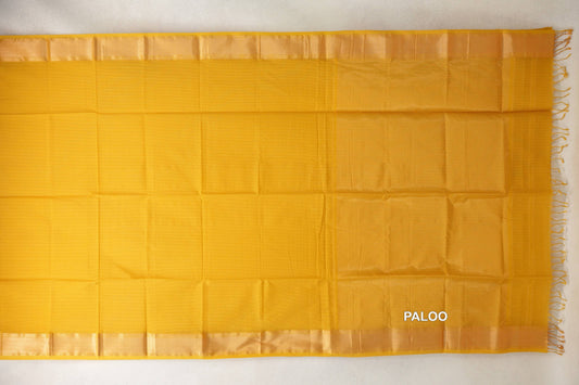 Mustard yellow Maheshwari silk cotton saree laid flat, showing a plain body, lustrous borders and a tonal pallu with tassels at the right edge.