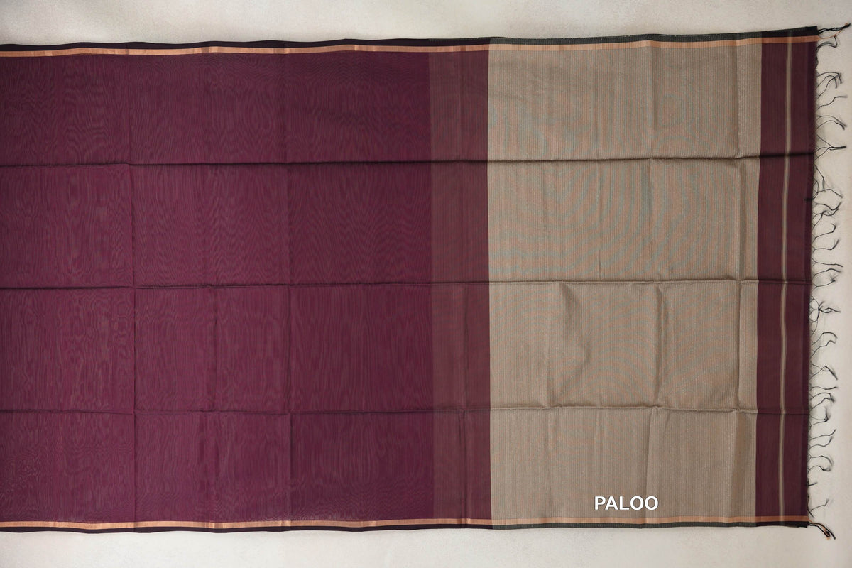 Maheshwari silk cotton saree laid flat, showing a wine maroon body, sand beige pallu, narrow striped borders and a fringed end.