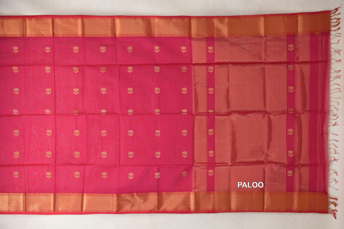 Deep Rani Pink Maheshwari silk cotton saree laid flat, showing small gold-toned floral motifs, broad woven borders and a striped pallu with tassels.