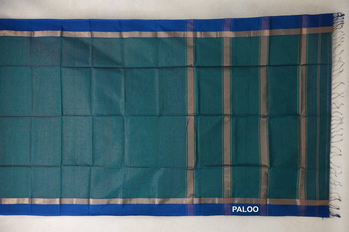 Teal green Maheshwari silk cotton saree laid flat, with royal blue borders, silver-toned bands and a striped pallu with tassels.
