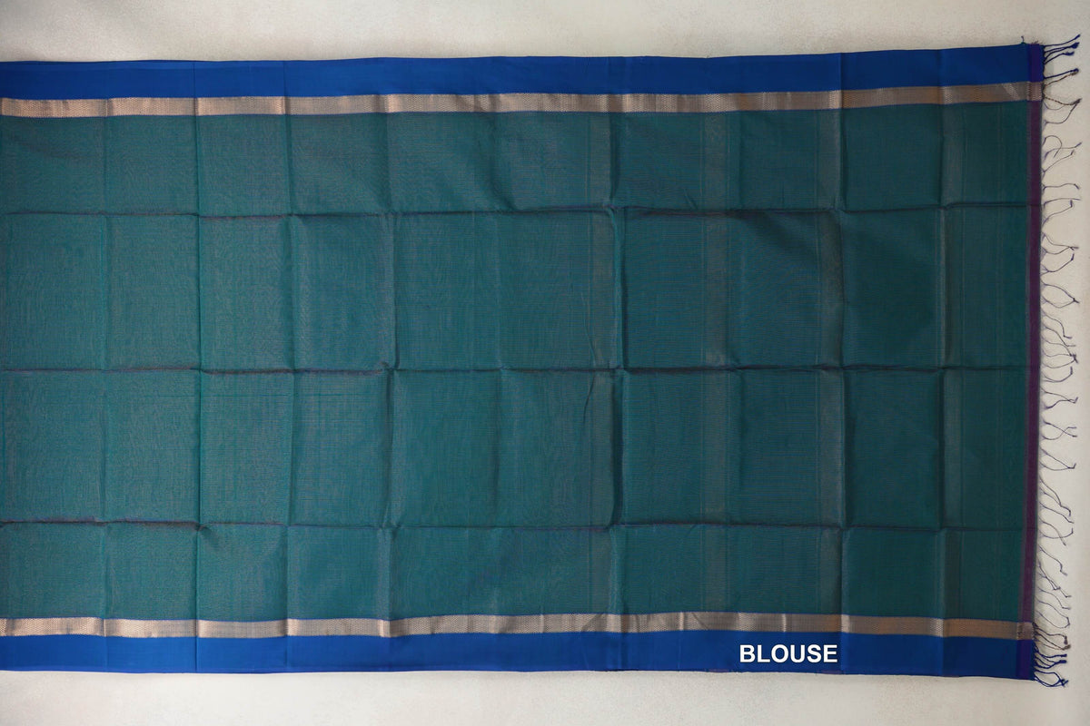 Teal green Maheshwari silk cotton blouse fabric laid flat, with royal blue borders, narrow metallic-patterned bands and tassels at one end.