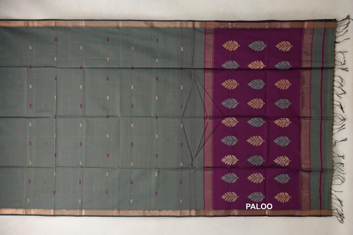 Sage green Maheshwari silk cotton saree laid out with small scattered motifs, gold-toned borders and a deep magenta leaf-patterned pallu with tassels.