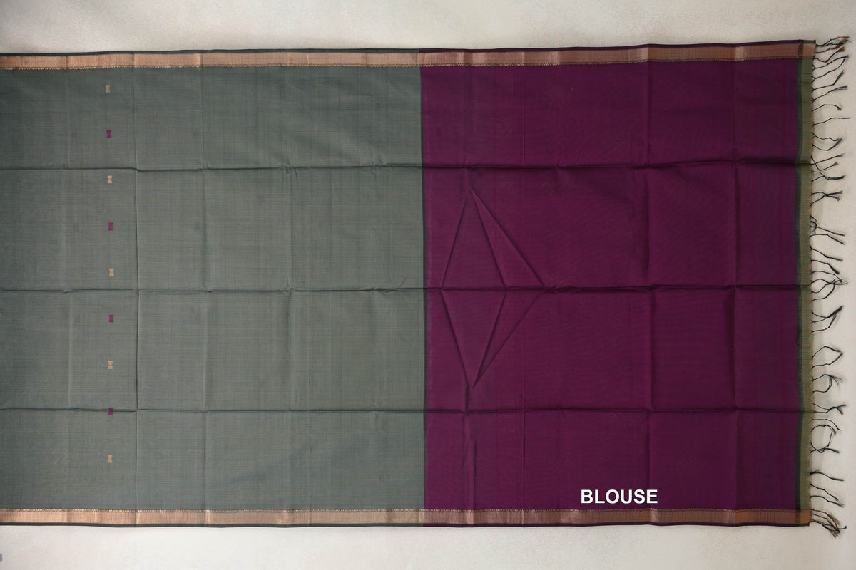 Sage green Maheshwari silk cotton saree laid flat with tiny scattered motifs and deep sage borders beside a deep magenta blouse piece with tassels.