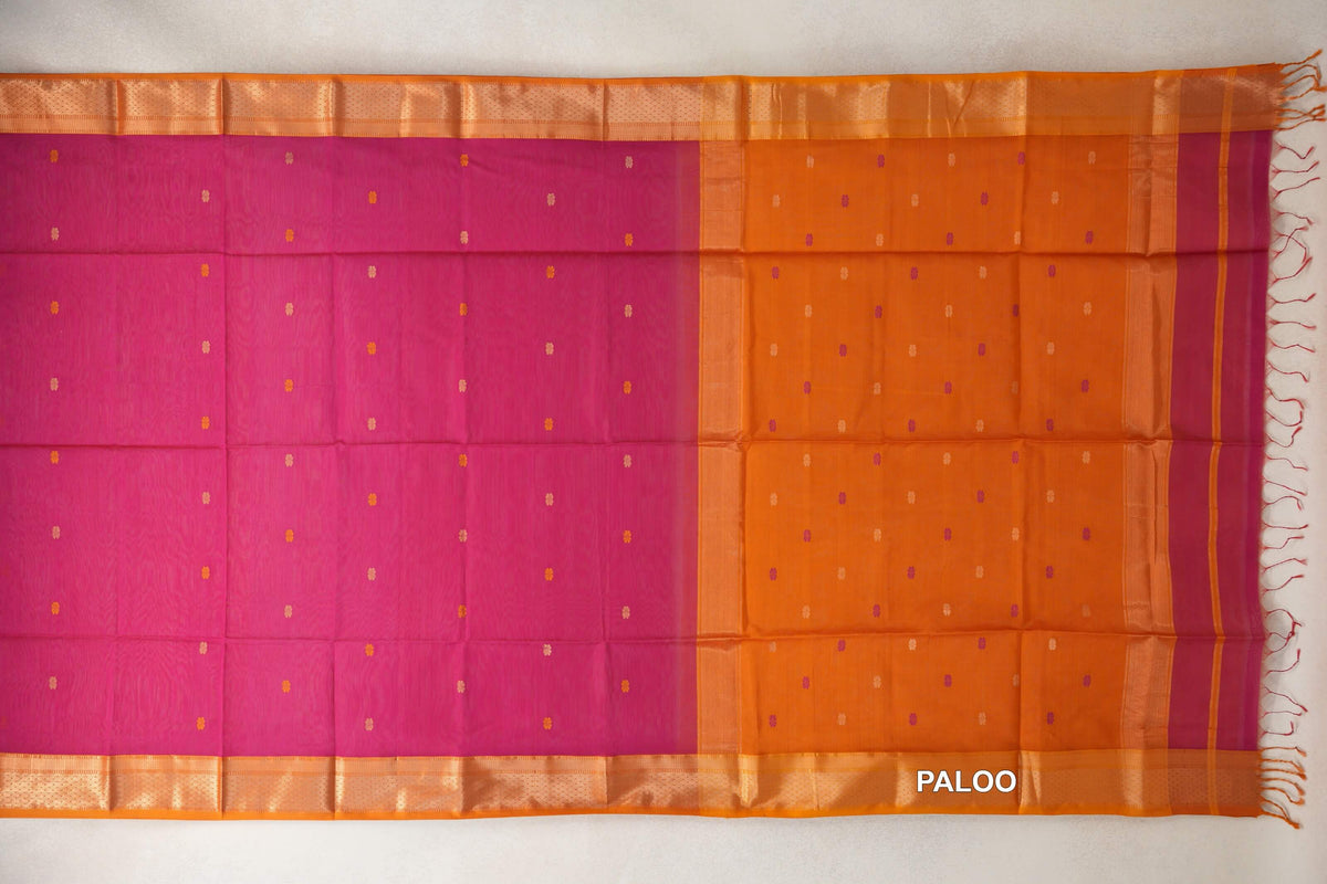 Rani pink Maheshwari silk cotton saree laid flat, with scattered small accents, deep orange borders and pallu, and tassels at the end.