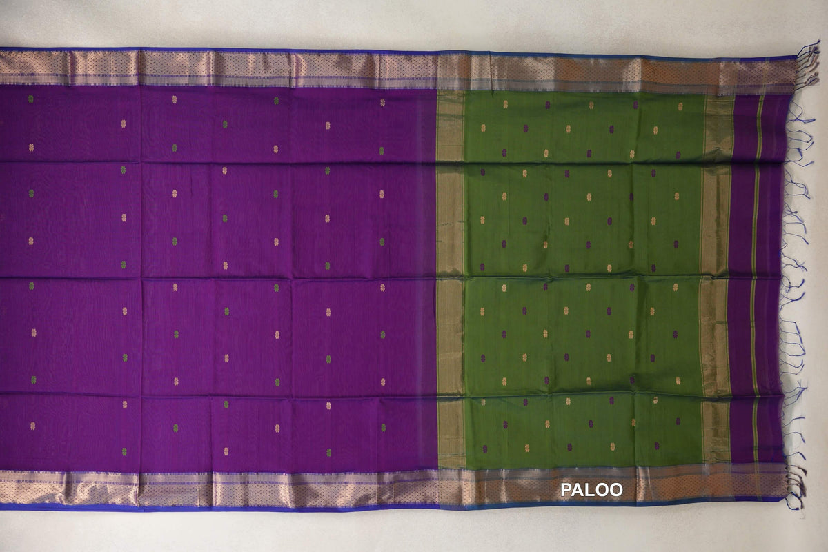 Maheshwari silk cotton saree laid flat, with a violet purple body, small scattered motifs, an olive green pallu and patterned borders edged in royal blue.