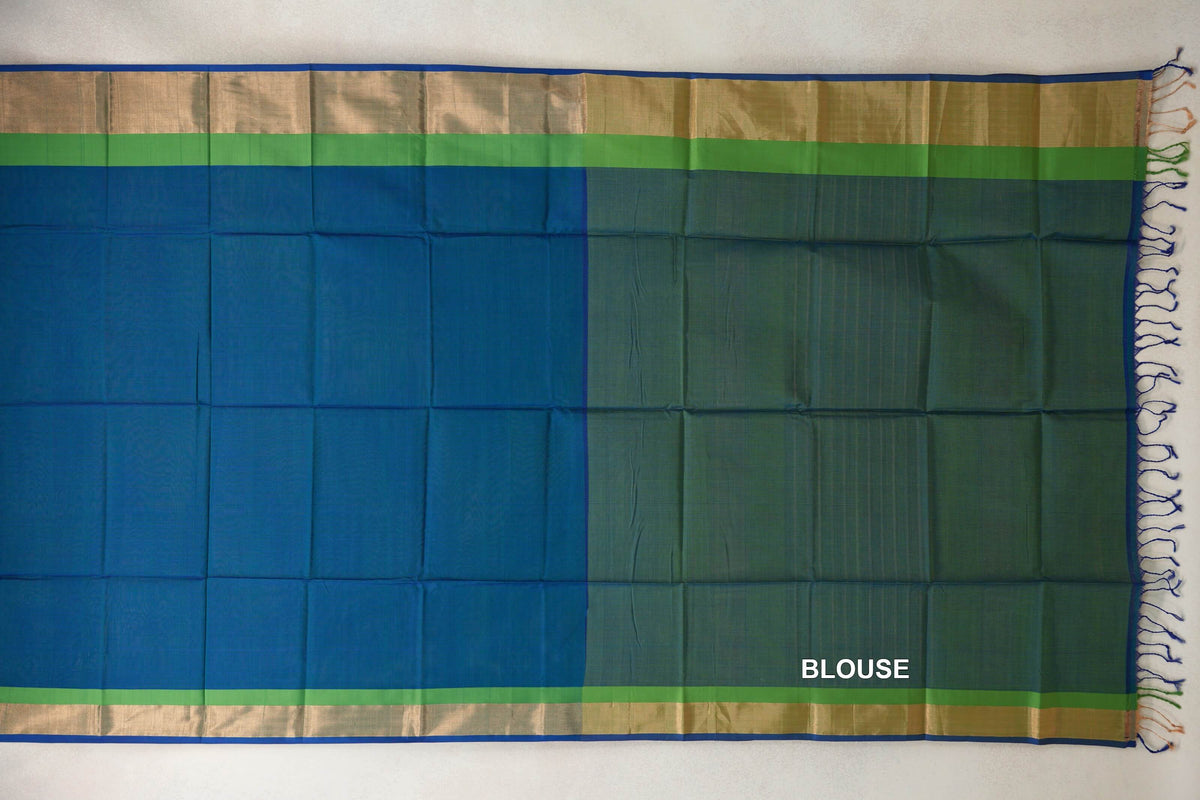 Maheshwari silk-cotton saree laid flat, showing a peacock blue body, a blouse section, parrot green and gold-toned borders with royal blue edges, and end tassels.