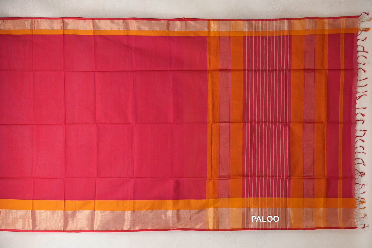 Maheshwari silk cotton saree laid open, showing a deep rani pink body, deep orange borders with pinkish red selvedge, and a striped pallu with tassels.
