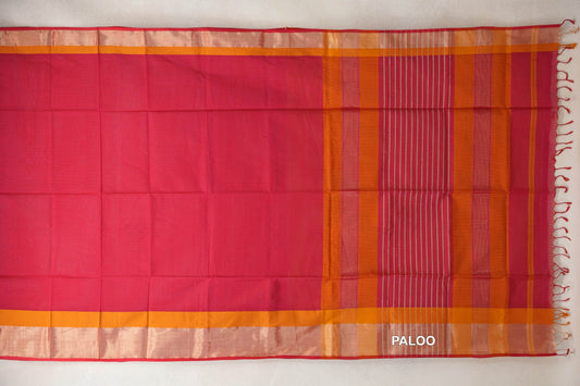 Maheshwari silk cotton saree laid open, showing a deep rani pink body, deep orange borders with pinkish red selvedge, and a striped pallu with tassels.