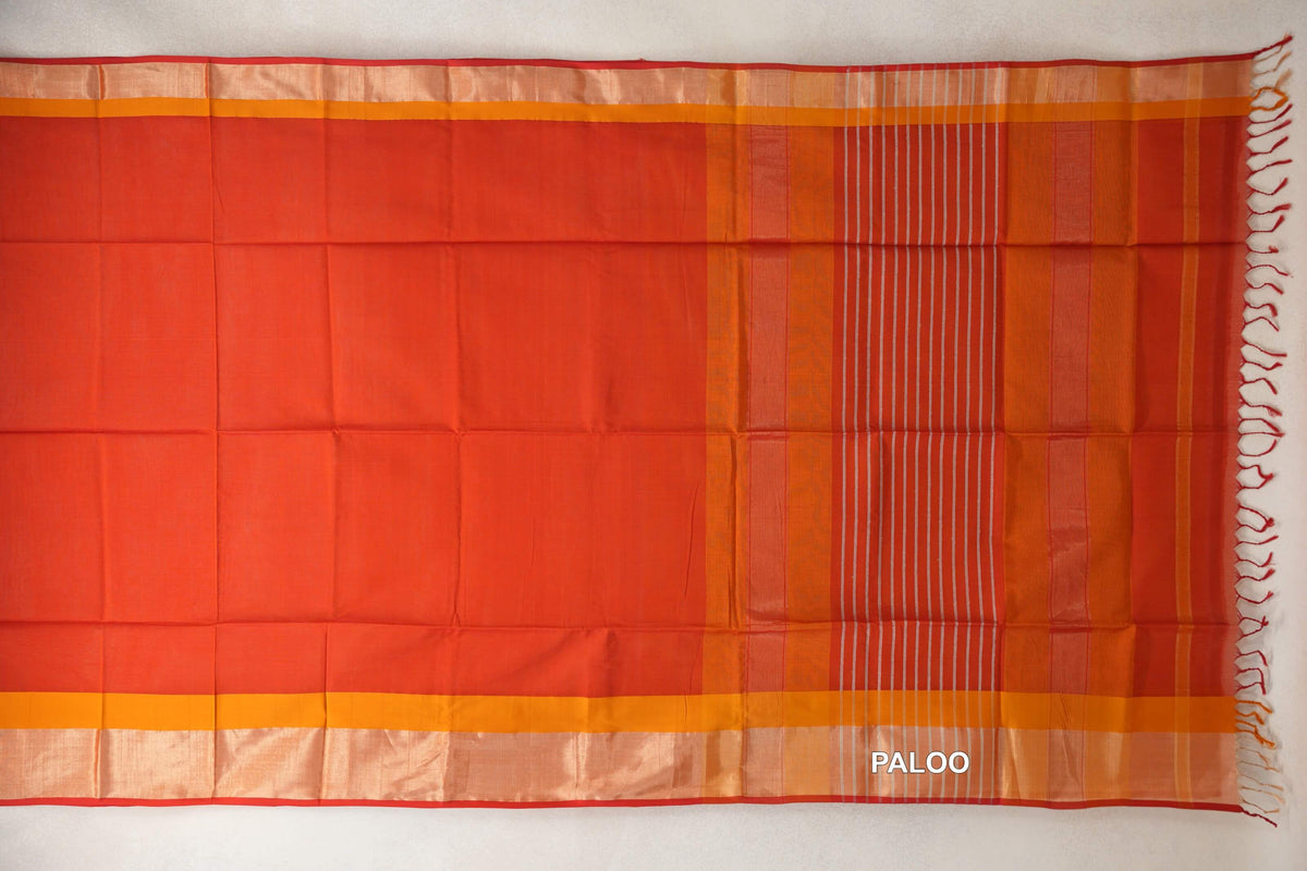 Tomato red Maheshwari silk cotton saree laid flat, with mustard orange borders, red selvedge and a striped pallu with tassels.