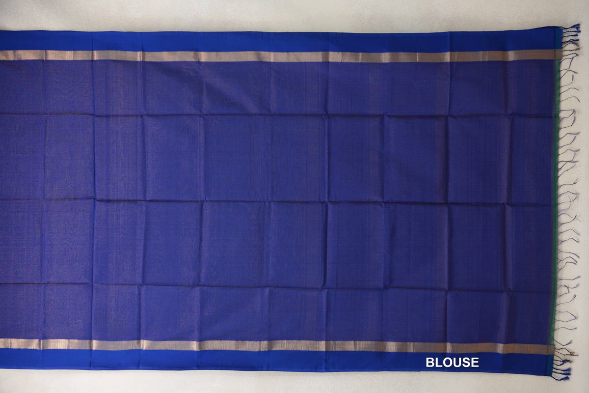 Deep royal blue Maheshwari silk-cotton blouse fabric spread flat, with narrow patterned bands along both edges and tassels at one end.
