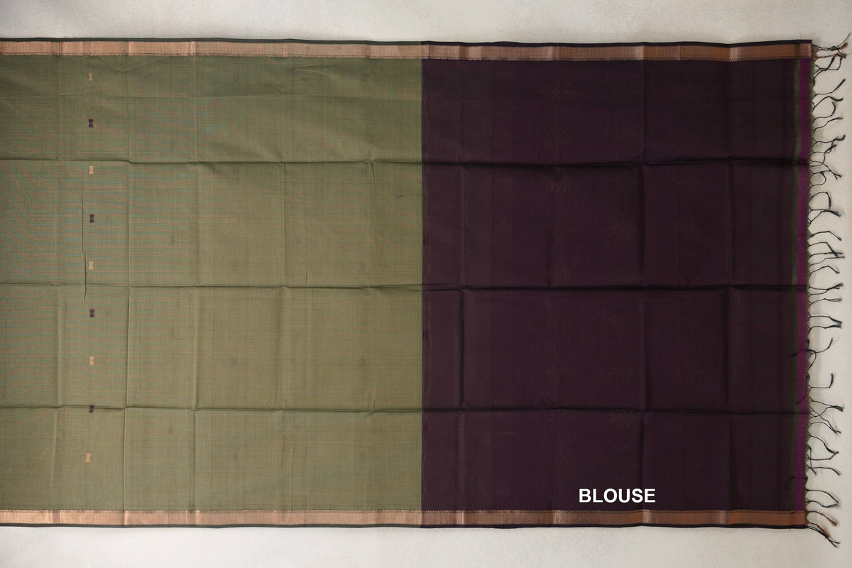 Spread-out Maheshwari silk cotton saree with a muted olive green body, small scattered accents and narrow borders, beside a deep wine plum blouse panel.