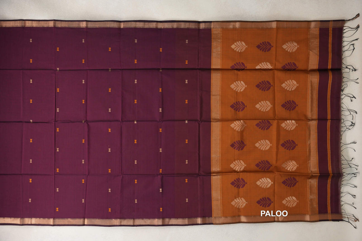 Deep Wine Maheshwari silk cotton saree laid flat with tiny motifs, gold-toned borders and a Deep Mustard Orange leaf-patterned pallu with tassels.