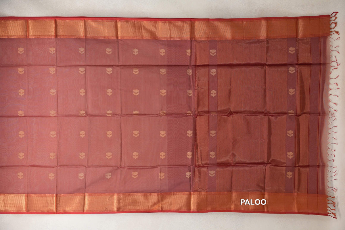Dusty rose Maheshwari silk cotton saree laid flat, with small floral motifs, red-edged copper-toned borders and a striped pallu with tassels.
