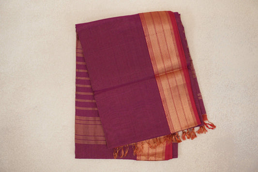 Folded deep magenta Maheshwari silk cotton saree with fine stripes, a broad patterned border, Rani Pink selvedge and tassels.