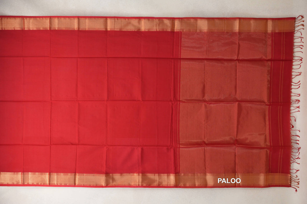 Vermilion red Maheshwari silk cotton saree spread open, with a plain body, metallic-look borders and a striped pallu with tassels.