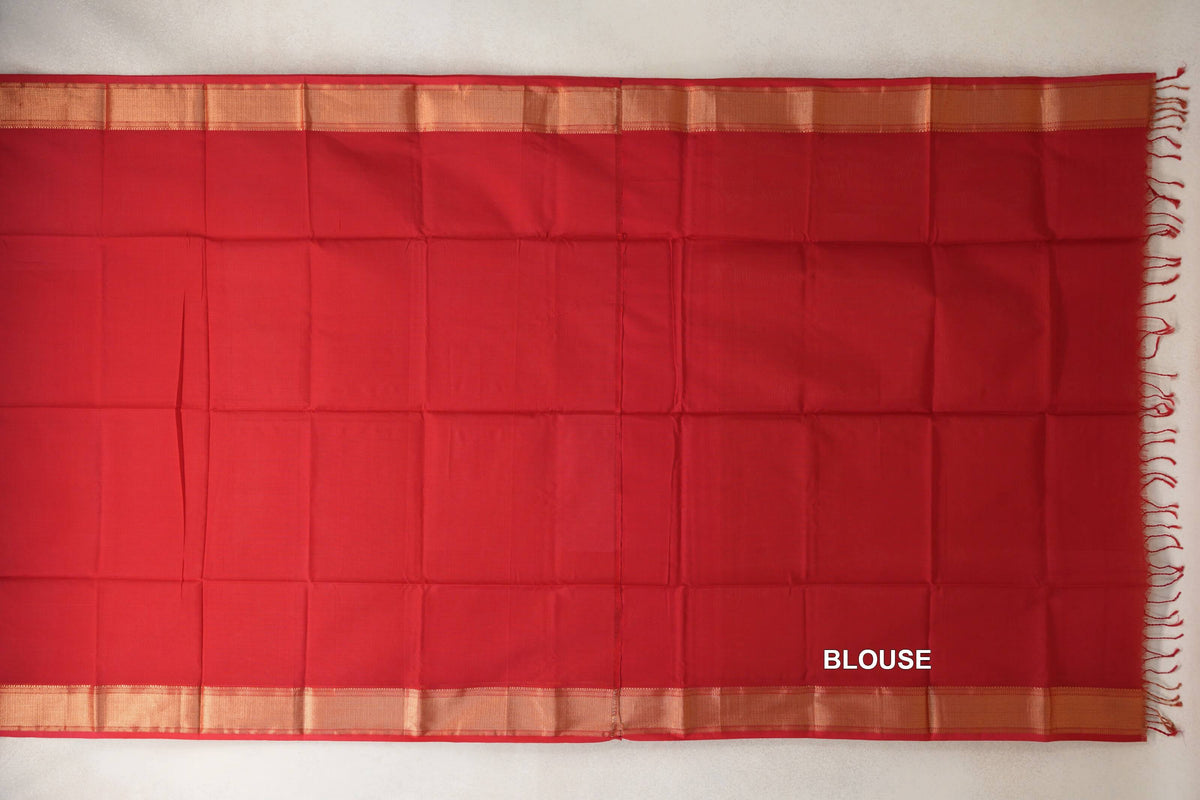 Vermilion red silk cotton blouse section laid flat, with a plain body, gold-toned bands along both edges and red fringe at one end.