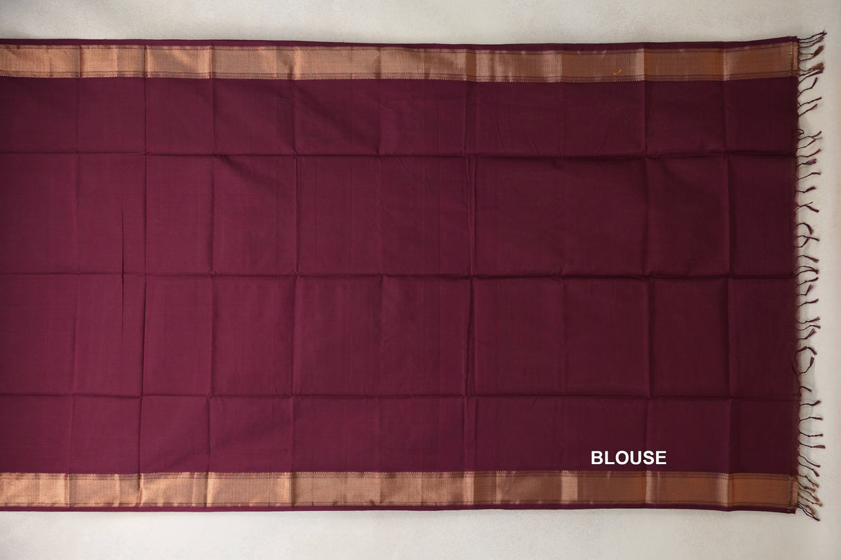 Deep wine Maheshwari silk-cotton blouse piece laid flat, with a plain center, copper-toned borders along both sides and tassels at one end.