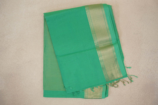 Folded sea green Maheshwari silk cotton saree with fine woven stripes, a gold-toned patterned border and tassels at one end.