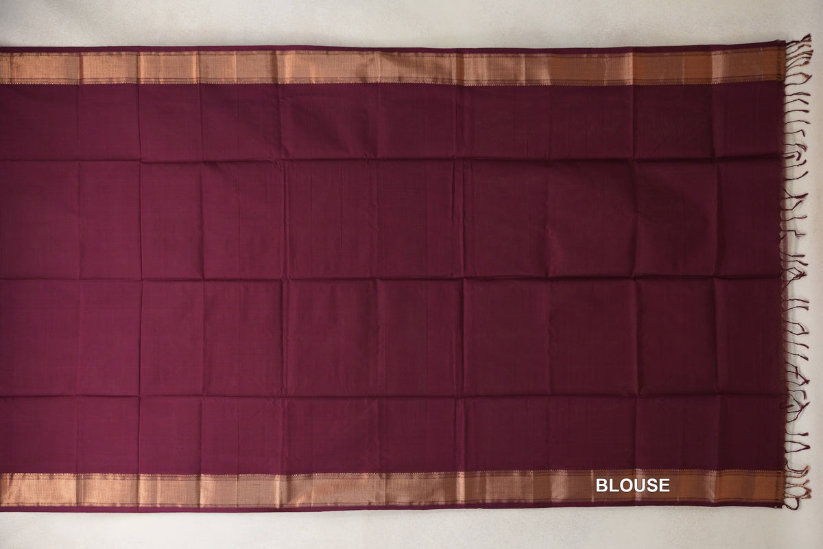 Deep wine Maheshwari silk cotton blouse piece laid flat, with a plain body, copper-toned borders along both sides and tassels at one end.