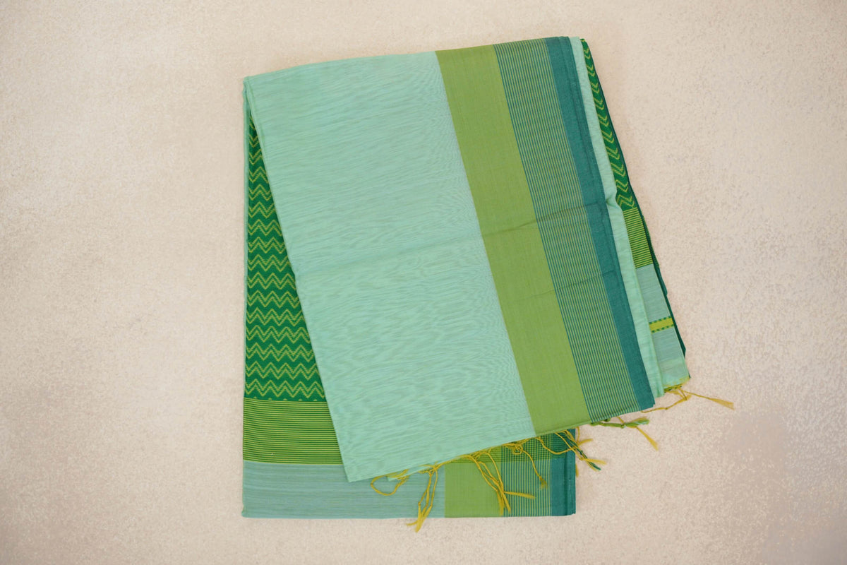 Folded mint green Maheshwari silk cotton saree with a parrot green border, fine teal stripes, a zigzag-patterned layer and yellow tassels.