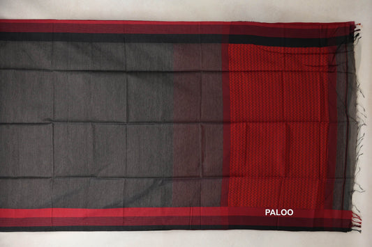 Charcoal grey Maheshwari silk cotton saree laid flat, with red and dark striped borders and a red zigzag-patterned pallu with tassels.