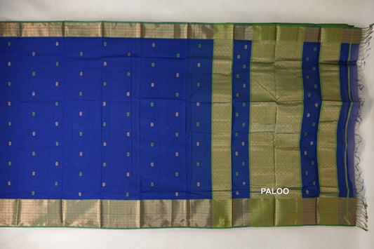 Maheshwari silk cotton saree laid flat, with a deep royal blue body, small scattered motifs, forest green patterned borders and pallu, and fringe.