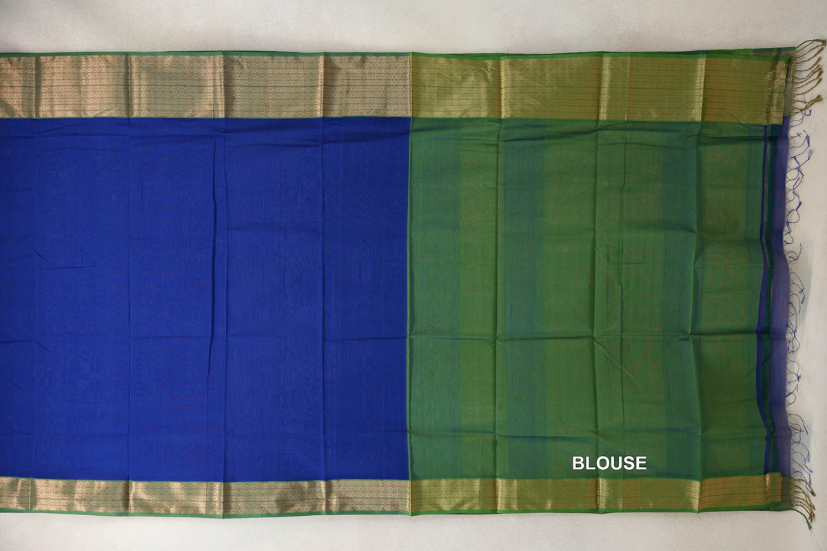 Maheshwari silk cotton saree laid flat, with a deep royal blue body, forest green blouse section, patterned gold-toned borders and tassels at one end.