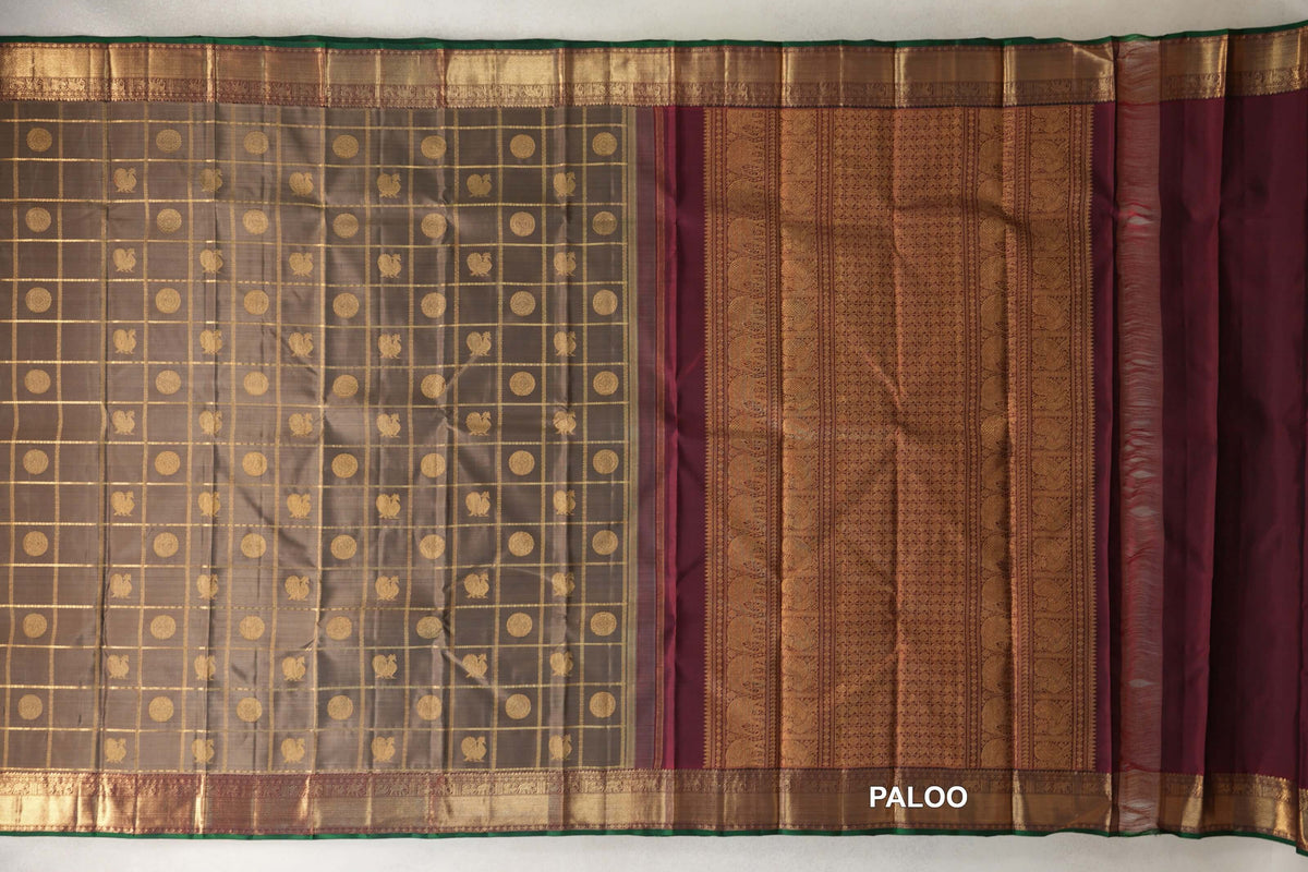 Spread-out olive green Kanjivaram silk saree with a gold checked body, deep maroon patterned pallu and gold borders edged in bottle green.